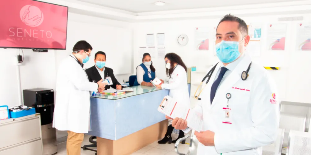 Profesionales médicos y pacientes interactuando amigablemente en clínica SENETO